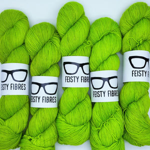 Five skeins of bright green yarn with 'Feisty Fibres' labels on a white background