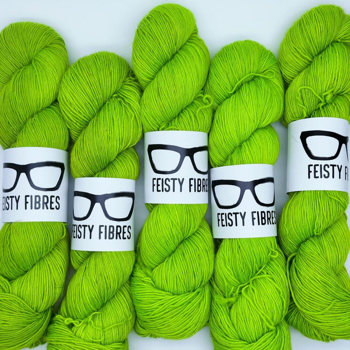 Five skeins of bright green yarn with 'Feisty Fibres' labels on a white background